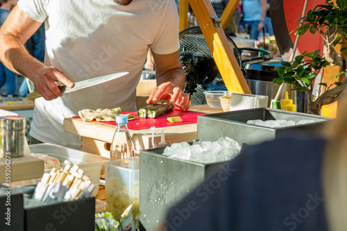 Chef making traditional sushi at outdoor kitchen event.