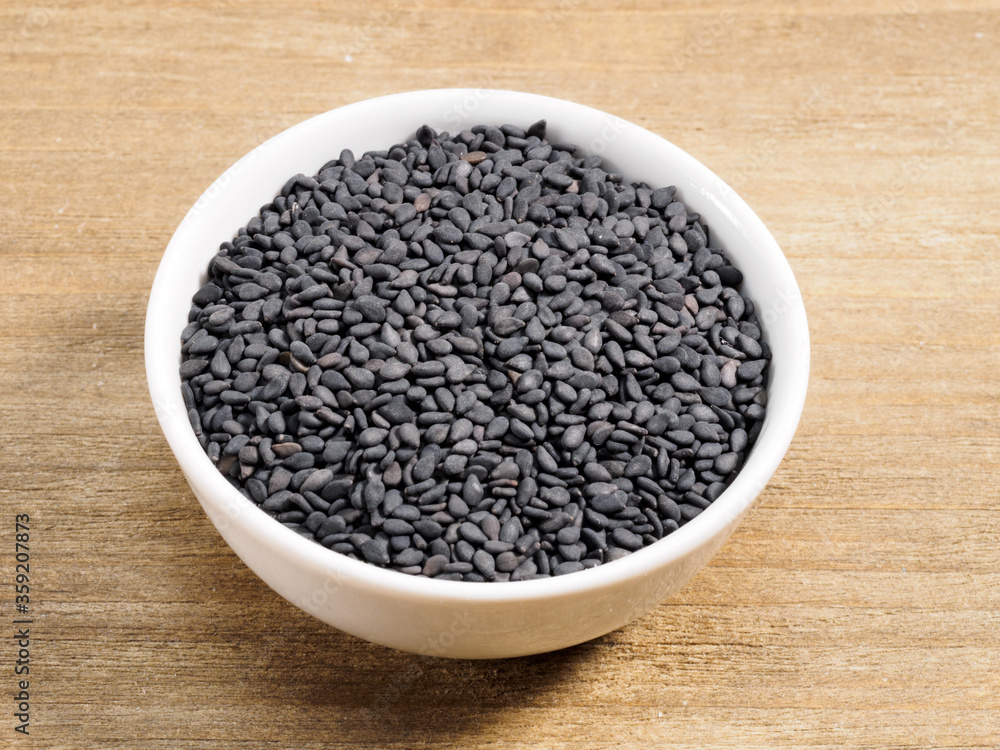Spice black cumin in white bowl on brown wood background Spice black cumin in white bowl on brown wood background