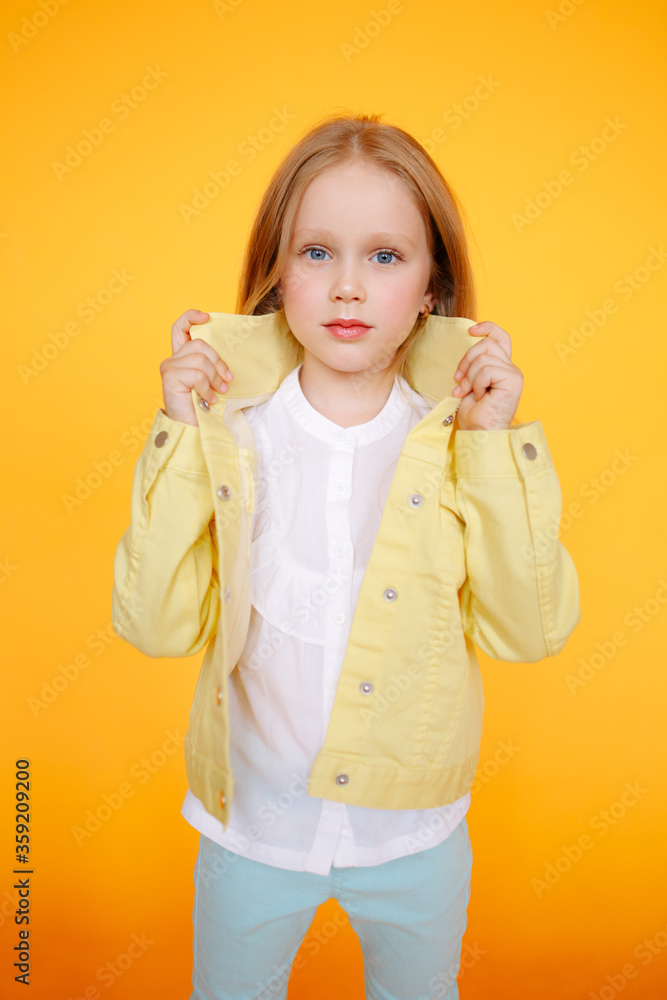 Beautiful portrat of young little girl in yellow studio and yellow bright clothes. Cute blonde child with plain healthy skin. Studio fashion model portrait