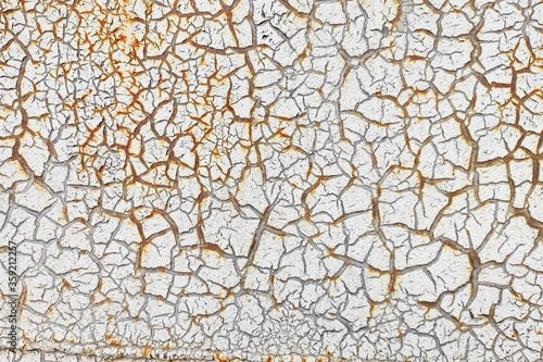 White cracked paint is applied to a rusty surface