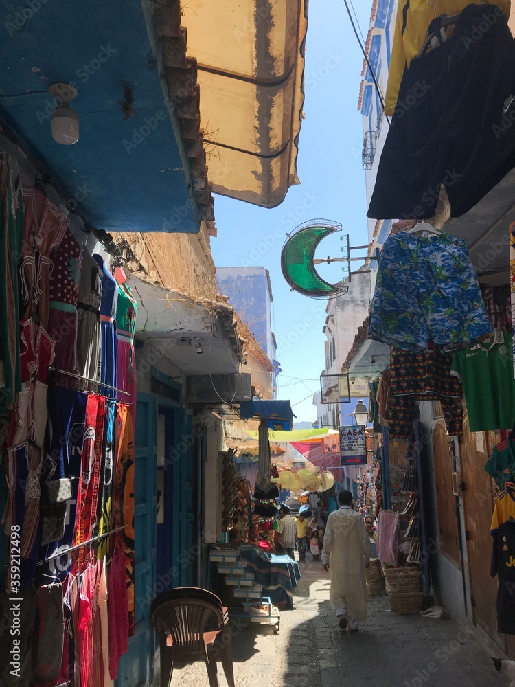 Obraz premium Chefchaouen, Morocco - July 29, 2019: A man walks past the handicraft stalls of the blue-painted alleys of the Medina.