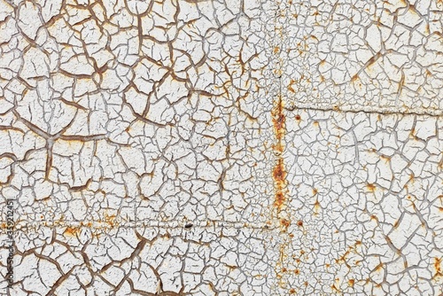 White cracked paint is applied to a rusty surface