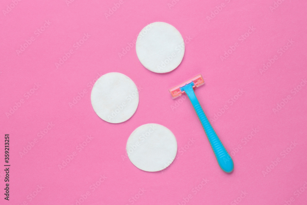 Beauty still life, minimalism. Plastic epilator razor with cotton circles on pink background. Women's accessories for beauty care. Top view Beauty still life, minimalism. Plastic epilator razor with cotton circles on pink background. Women's accessories for beauty care. Top view