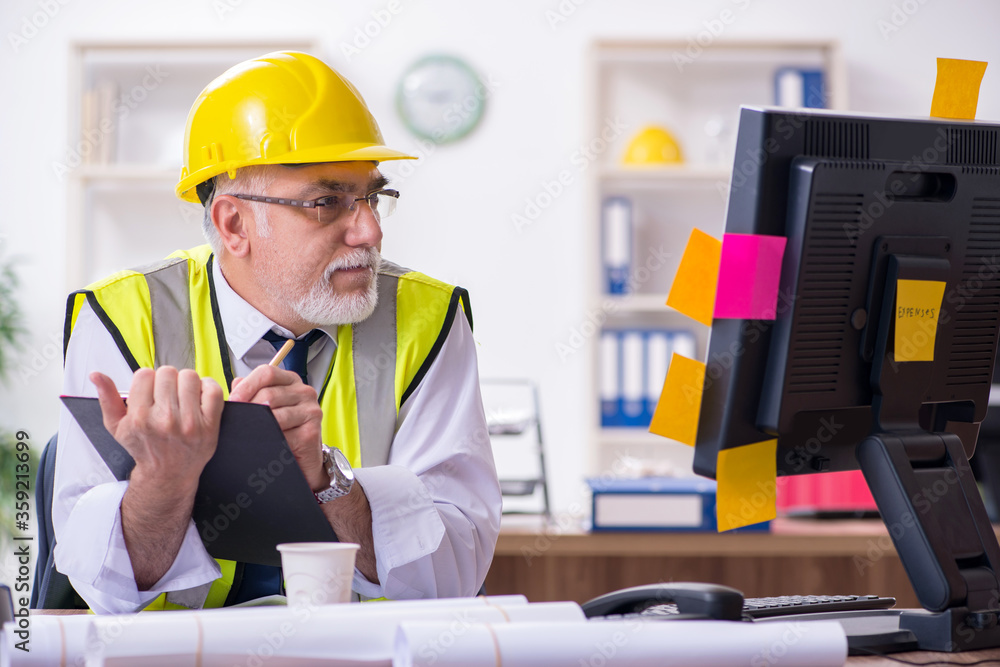 Old male architect working in the office Old male architect working in the office