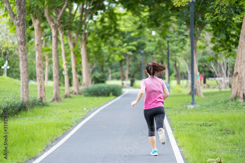 Young adult female in sportswear running in the park outdoor, runner woman jogging on the road, asian Athlete walking and exercise in morning. Fitness, wellness, healthy lifestyle and workout concepts