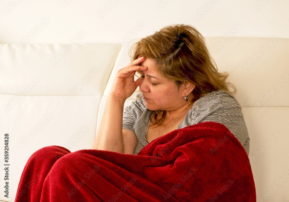 Woman lying with her hand on her head with a painful expression Woman lying with her hand on her head with a painful expression