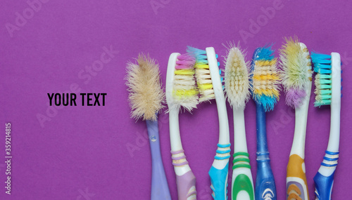 Old used toothbrushes on purple background. Dental care concept. Top view. Copy space