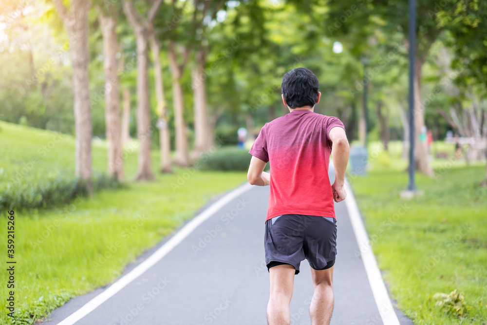 Young adult male in sportswear running in the park outdoor, runner man jogging on the road, asian Athlete walking and exercise in morning. Fitness, wellness, healthy lifestyle and workout concepts