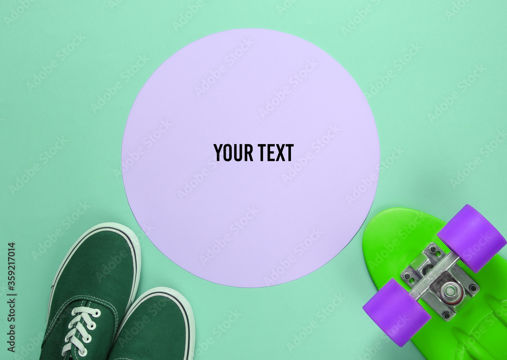 Fototapeta premium Cruiser board and sneakers on green background with a pink pastel circle in the middle for copy space. Youth hipster concept. Summer fun. Top view