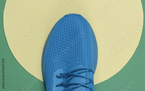 Blue sport sneaker ongreen background with yellow pastel circle. Youth hipster concept. Top view photo