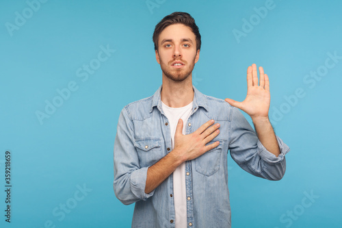 Photography I swear! Portrait of honest responsible man in worker denim shirt giving evidence with raised hand as telling only truth, making loyalty promise oath