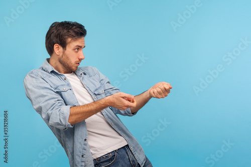 Fotografie Portrait of hardworking persistent man in worker denim shirt pulling virtual rope, imitating to hold heavy object, striving and making great effort