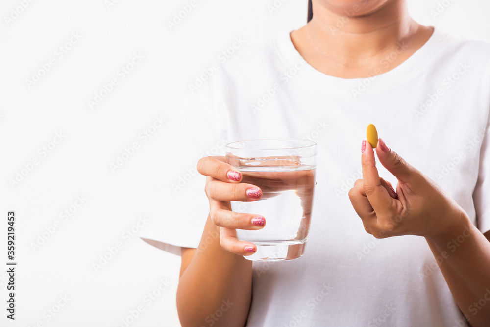 Closeup young Asian woman hold fish oil vitamin drugs in hand ready take medicines with a glass of water, studio shot isolated on white background, Healthcare and medical pharmacy concept Closeup young Asian woman hold fish oil vitamin drugs in hand ready take medicines with a glass of water, studio shot isolated on white background, Healthcare and medical pharmacy concept