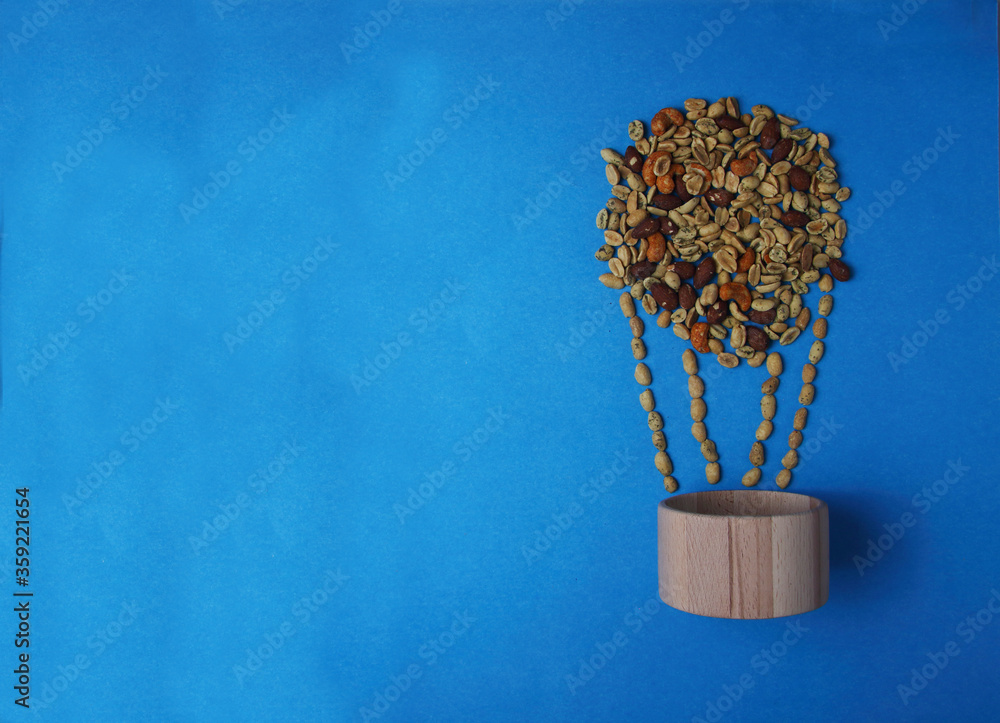 air-balloon made of nut mix and wooden bowl isolated on blue background flat lay