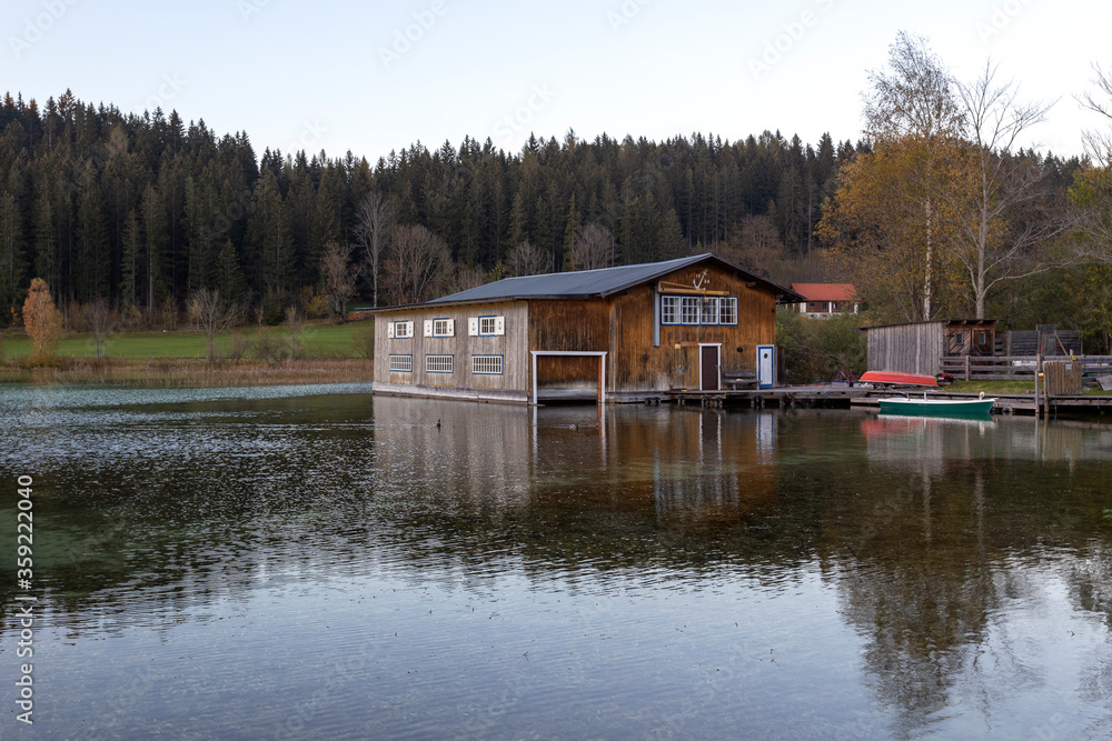 Obraz premium Erlaufsee - a mountain lake at the foot of the Alps in Lower Austria. Wooden yard standing in the water. Green boat parked on the right.