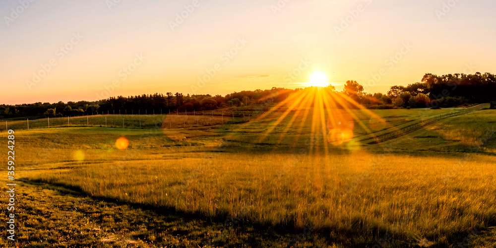 Beautiful sunset over a farmland, with sunburst, sunstars