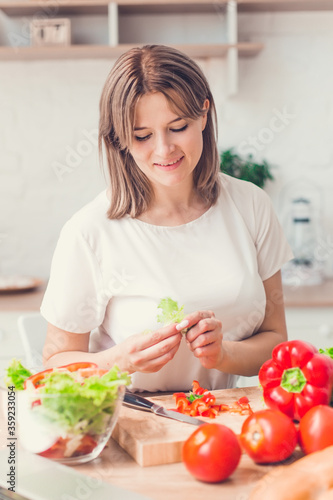 Woman cutting vegetables on salad on kitchen.