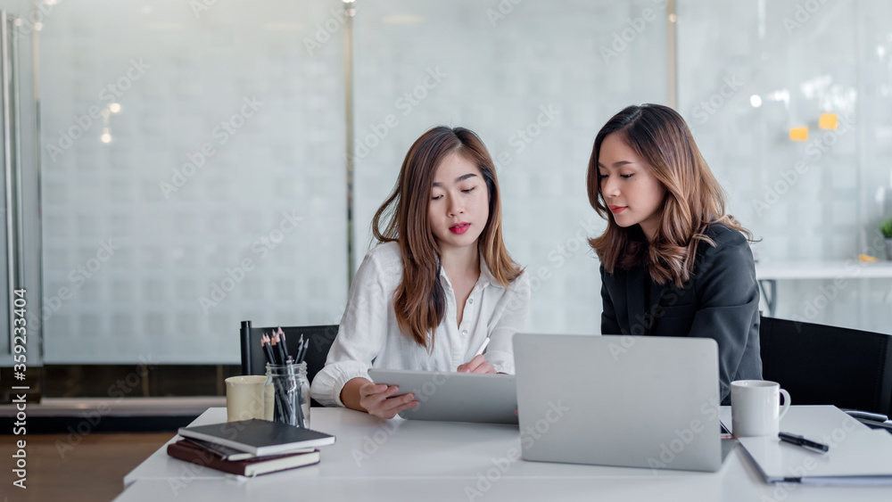 Two business women working together with a laptop computer to explain and discuss on business in the office. Two business women working together with a laptop computer to explain and discuss on business in the office.
