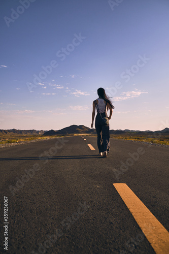 Asian girl walking along the road in between mountains. © Lnunes