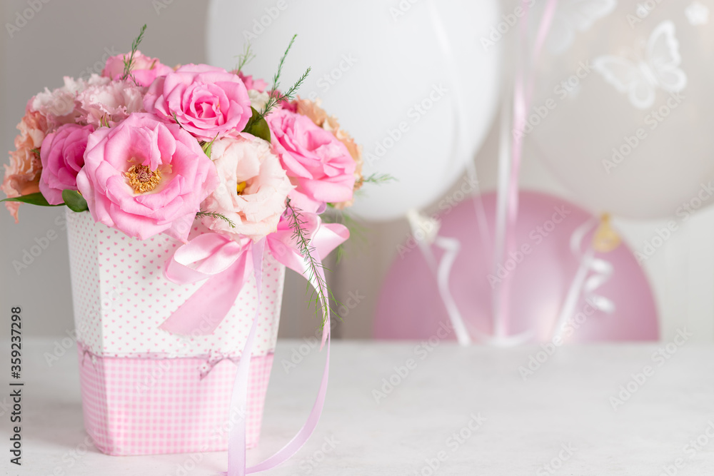 beautiful bouquet of pastel roses and eustomas in a box with a ribbon on a background of balloons. birthday party concept. place for text. horizontal image. beautiful bouquet of pastel roses and eustomas in a box with a ribbon on a background of balloons. birthday party concept. place for text. horizontal image.