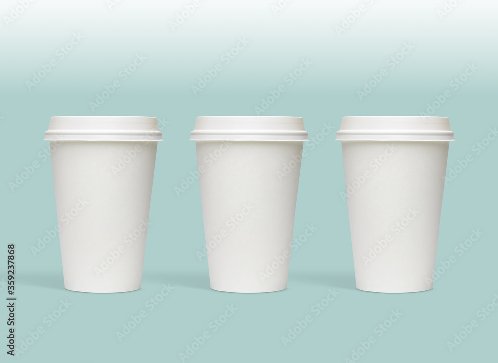 White blank medium size takeaway paper, carton or cardboard coffee cups with white caps packaging template mockup isolated on light green background White blank medium size takeaway paper, carton or cardboard coffee cups with white caps packaging template mockup isolated on light green background
