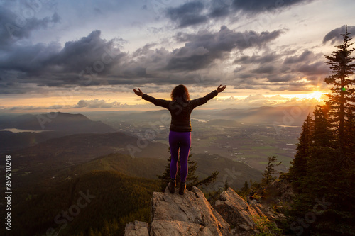 Adventurous Girl on top of a Rocky Mountain overlooking the beautiful Canadian Nature Landscape during a dramatic Sunset. Taken in Chilliwack  East of Vancouver  British Columbia  Canada.