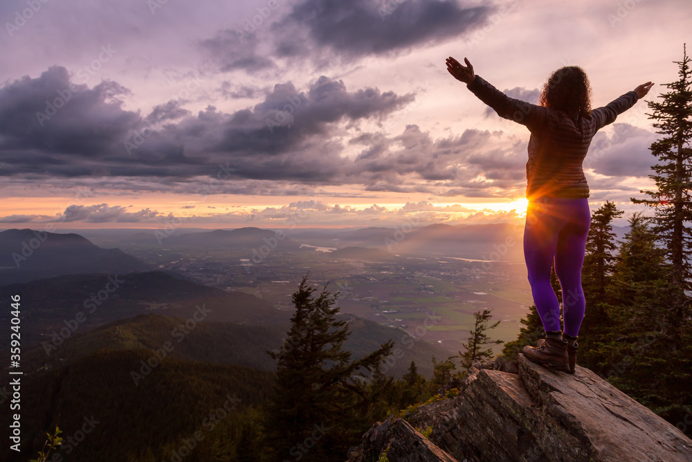 Adventurous Girl on top of a Rocky Mountain overlooking the beautiful Canadian Nature Landscape during a dramatic Sunset. Taken in Chilliwack, East of Vancouver, British Columbia, Canada.