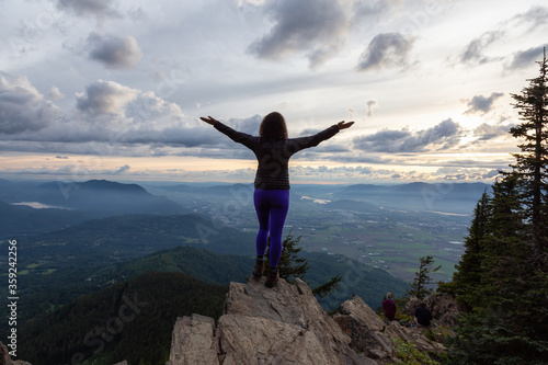 Adventurous Girl on top of a Rocky Mountain overlooking the beautiful Canadian Nature Landscape during a dramatic Sunset. Taken in Chilliwack, East of Vancouver, British Columbia, Canada. © edb3_16