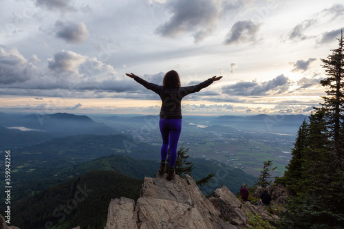 Adventurous Girl on top of a Rocky Mountain overlooking the beautiful Canadian Nature Landscape during a dramatic Sunset. Taken in Chilliwack, East of Vancouver, British Columbia, Canada.