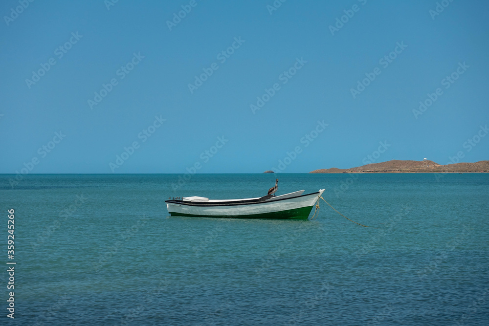 Lonely traditional Colombian fishing boat on sea water with clear water and blue sky - at Cabo de la vela, La guajira, Colombia