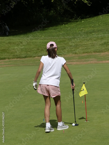 Young golfer on the putting Green vertical vue from back
