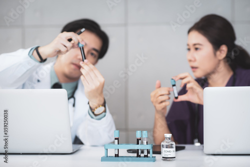 blur the medical team was meeting seriously in meeting room. About the vaccine used to treat patients infected with covid-19 or corona virus With a vaccine bottle and a blood sample placed on table
