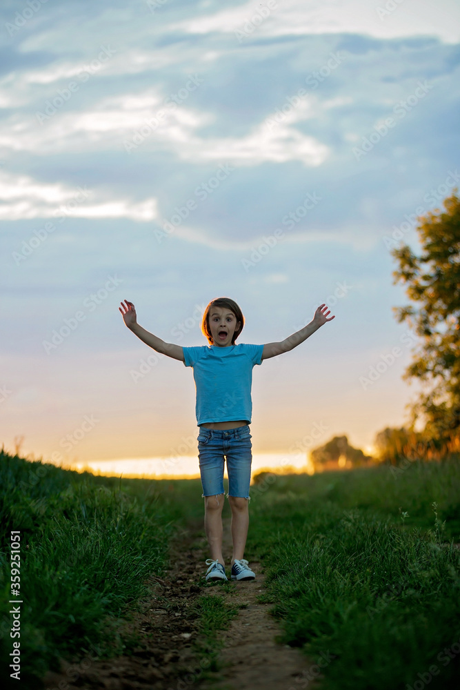 Happy child, holding pair of sneakers in hands, walking on a rural path Happy child, holding pair of sneakers in hands, walking on a rural path