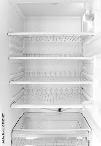 Empty open white fridge. Defrosted refrigerator without food.