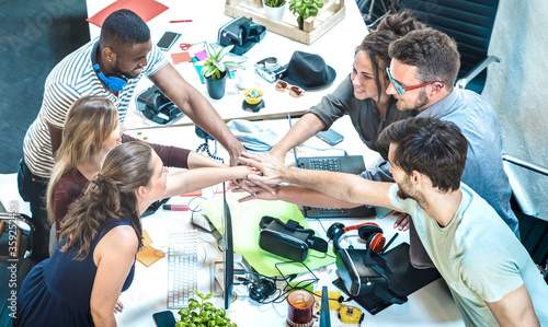 Young employee startup workers group stacking hands at urban studio during entrepreneurship brainstorming project - Business concept of human resources on working time - Start up internship at office photo