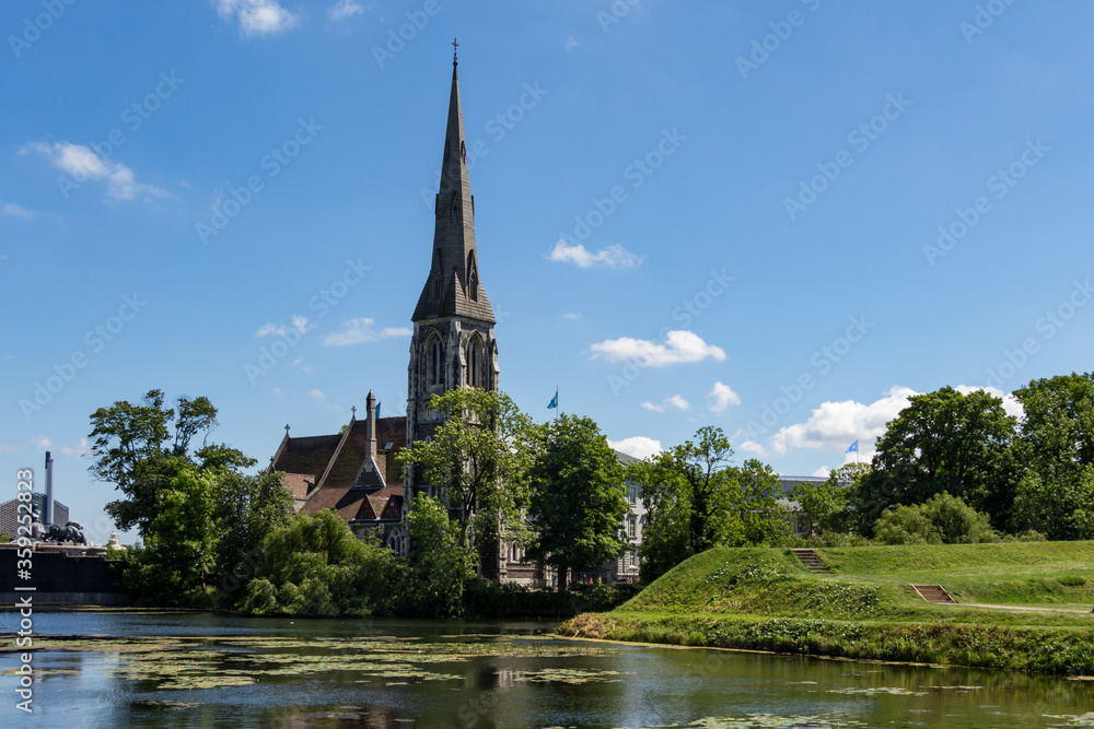 St Alban's English Church located next to the citadel Kastellet in Copenhagen, Denmark. Small lake in from of the church. Reflection in the water. Bright, sunny day.
