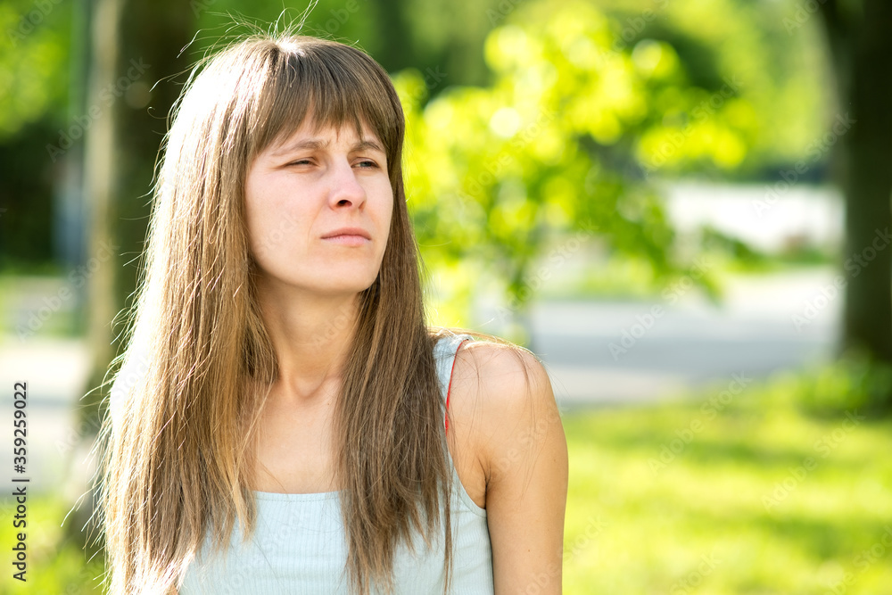 Naklejka premium Portrait of serious pretty young woman in summer park.