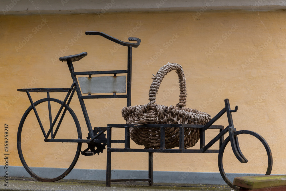 Classic bicycle standing next to the wall. Bicycle leaned on the wall. Basket on the bicycle.