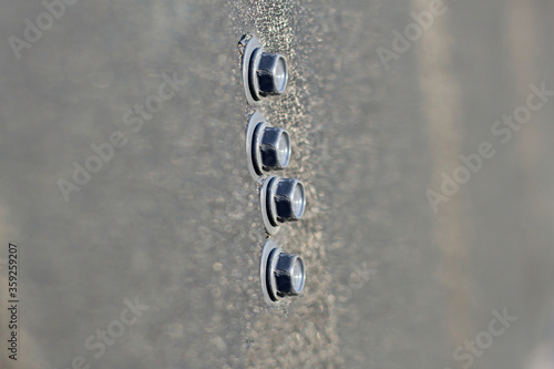 Set of metallic bolts fastened on iron sheet outdoors. Building, construction and repairing, copy space background. © bilanol