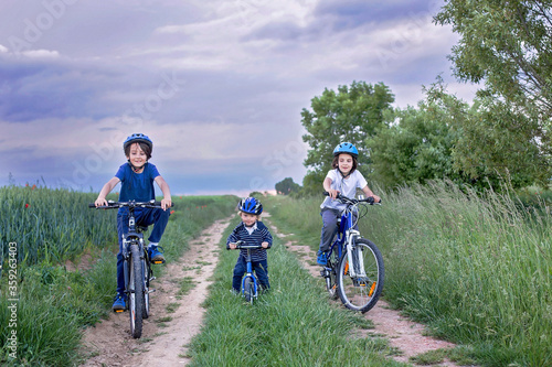 Children, riding bikes on rural path, summer evening