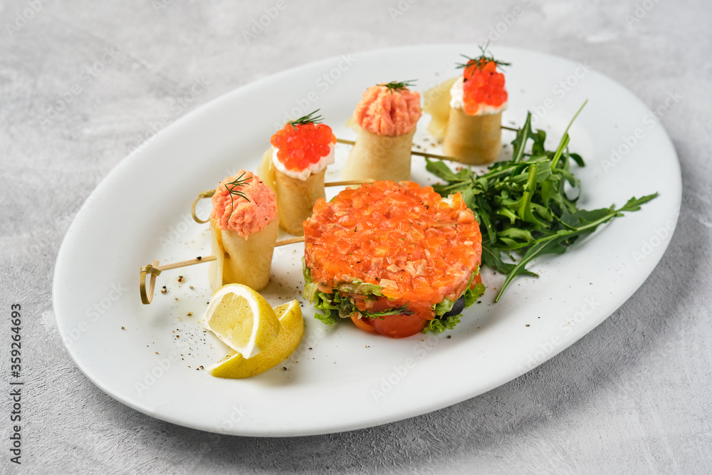Thin rolled pancakes, crepes with salmon and red caviar, fish tartare. Thin rolled pancakes, crepes with salmon and red caviar, fish tartare.