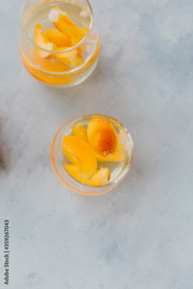 2 glasses with water, ice and slices of apricots. View from above
