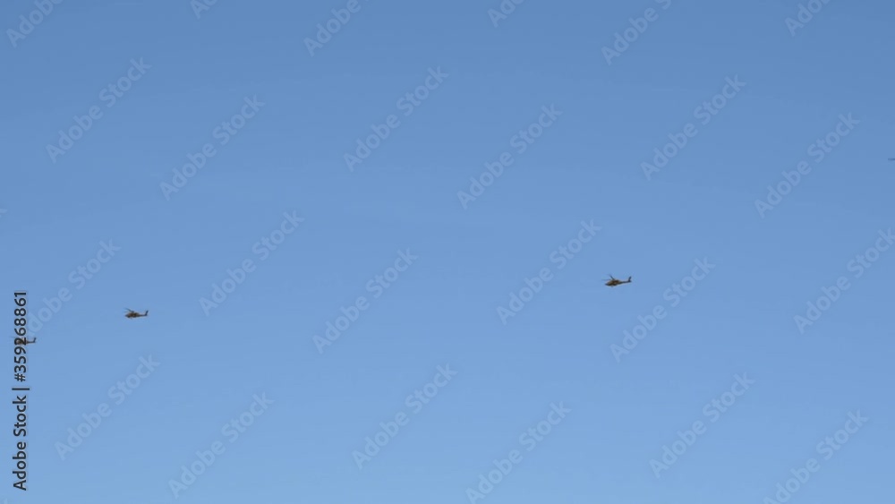 At a distance, a black helicopter formation leads a Chinook helicopter over the Sonoran Desert. At a distance, a black helicopter formation leads a Chinook helicopter over the Sonoran Desert.