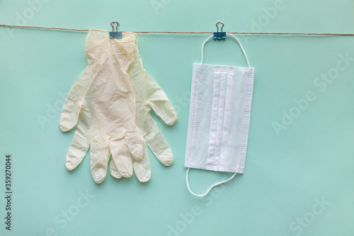 Medical mask and latex gloves are on the green paper background.