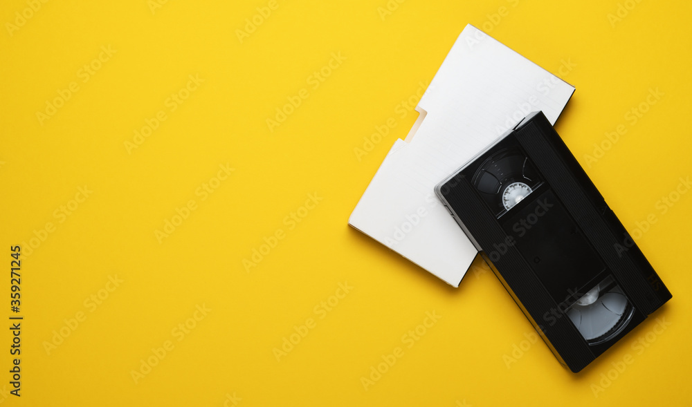 Old video cassette on a yellow background. Creative concept in retro style, 80s. Top view, minimalism. Old video cassette on a yellow background. Creative concept in retro style, 80s. Top view, minimalism.