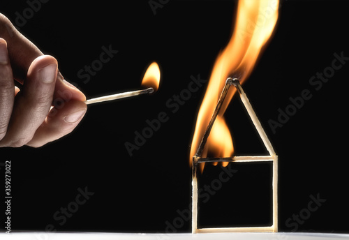 Foto Human sets fire to house from matches. On black