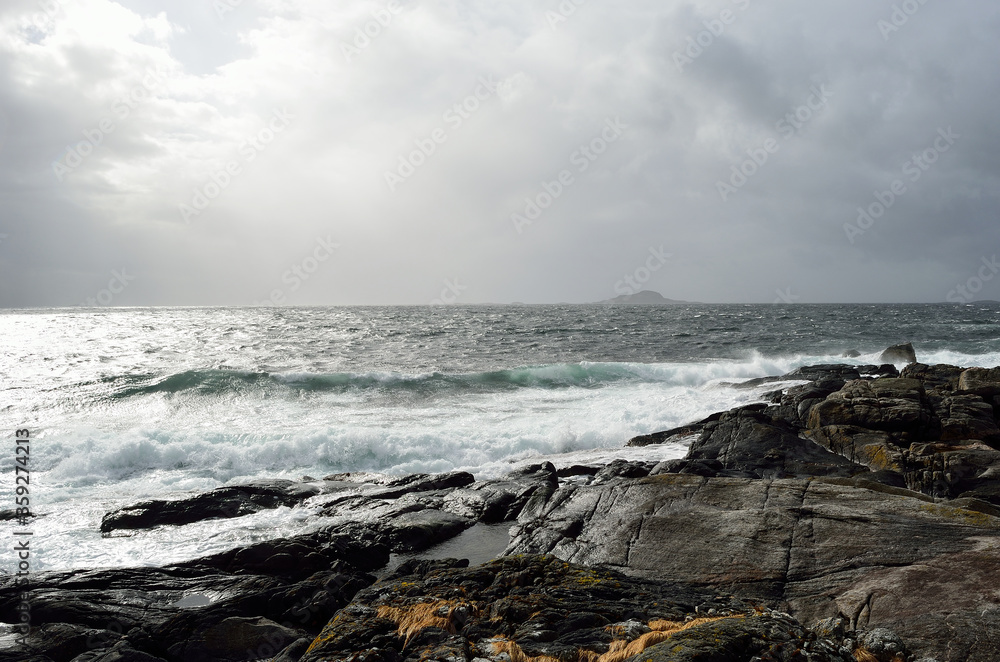 stormy windy day by the sea shore with majestic mountain in the distance on the island of Senja