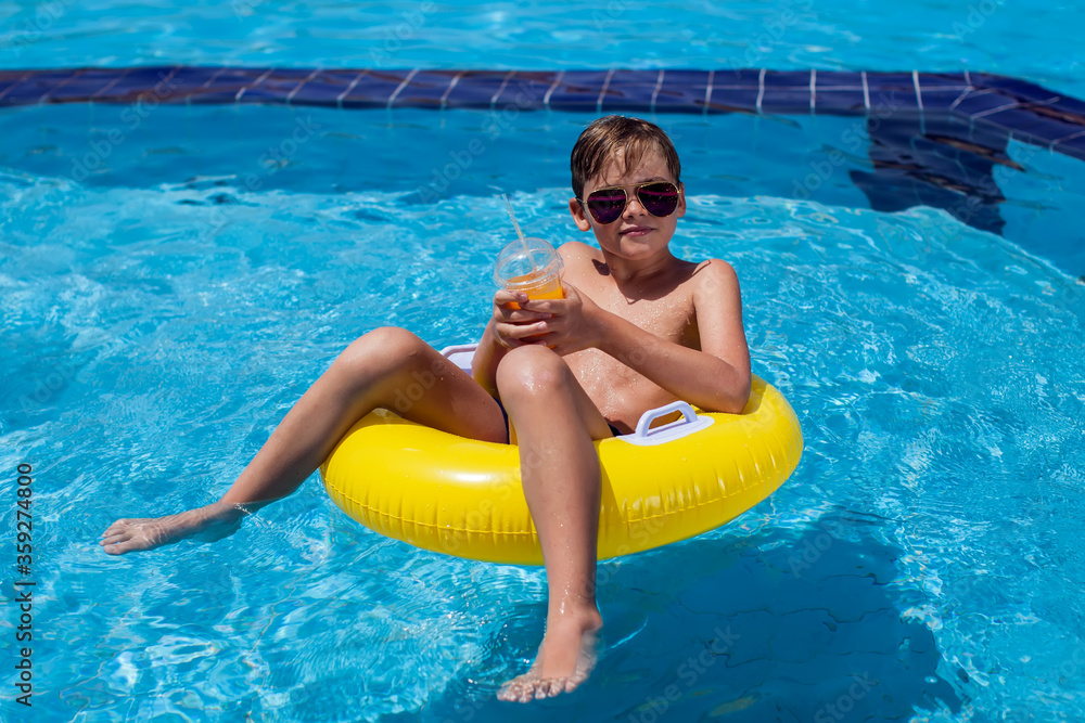 Kid boy holding juice in the swimming pool. Childhood, summer and vacation concept