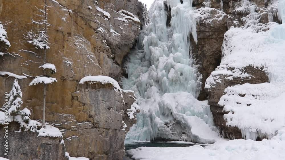 Frozen Waterfall Upper Falls Surrounded By Snow And Icy Rock In Johnston Canyon In Banff Frozen Waterfall Upper Falls Surrounded By Snow And Icy Rock In Johnston Canyon In Banff