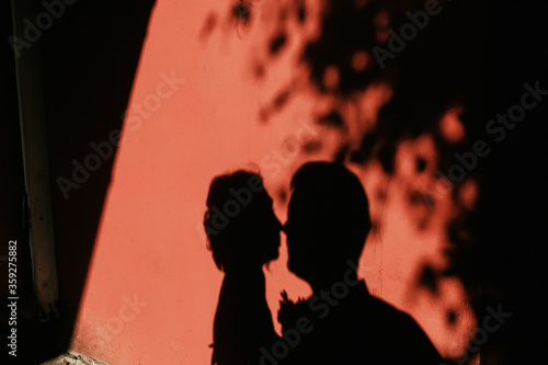 silhouette of a kissing couple on a red wall